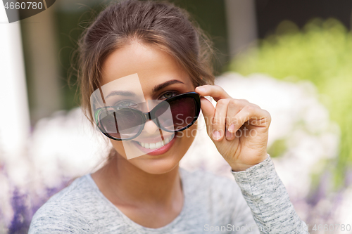 Image of happy young woman in sunglasses at summer garden