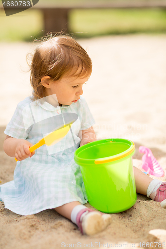 Image of little baby girl plays with toys in sandbox