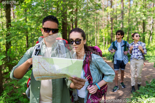 Image of friends with map and backpacks hiking in forest