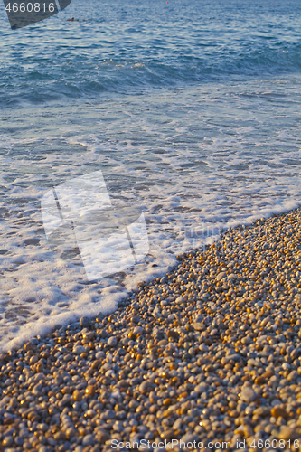 Image of Pebble stones by the sea. Waves of blue Tyrrhenian sea.