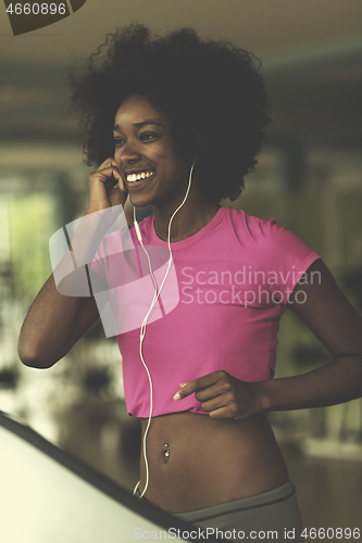 Image of afro american woman running on a treadmill