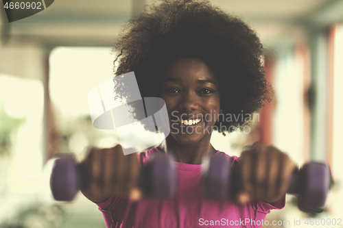 Image of woman working out in a crossfit gym with dumbbells