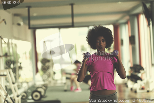 Image of woman working out in a crossfit gym with dumbbells