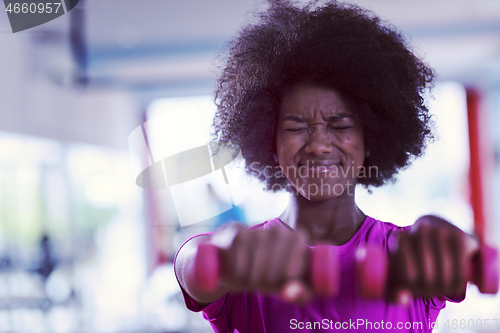 Image of woman working out in a crossfit gym with dumbbells