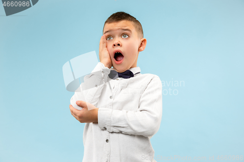 Image of The young attractive teen boy looking suprised isolated on blue