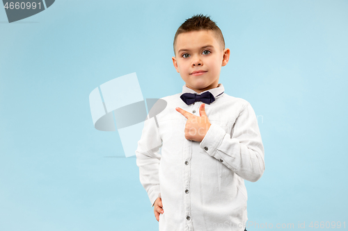 Image of The happy teen boy standing and smiling against blue background.