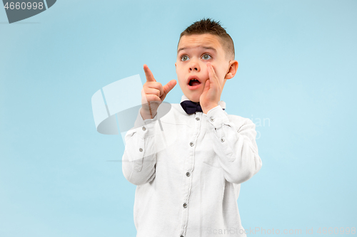 Image of The young attractive teen boy looking suprised isolated on blue