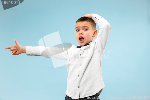 Image of The young attractive teen boy looking suprised isolated on blue