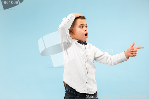 Image of The young attractive teen boy looking suprised isolated on blue