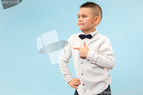 Image of The happy teen boy standing and smiling against blue background.