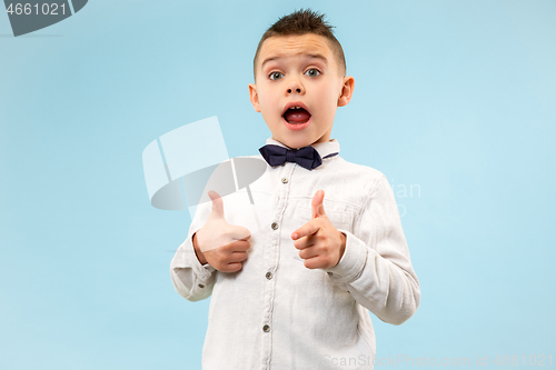 Image of The young attractive teen boy looking suprised isolated on blue