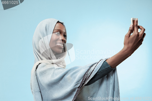 Image of The beautiful young black muslim girl wearing gray hijab, with a happy smile on her face.