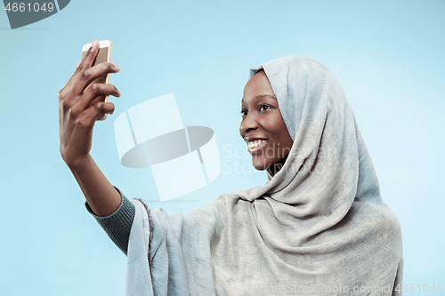 Image of The beautiful young black muslim girl wearing gray hijab, with a happy smile on her face.