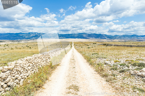 Image of Dirt road leading trough dry rocky Mediterranean coastal lanscape of Pag island, Croatia in summertime