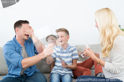 Image of Happy young family playing card game at home.