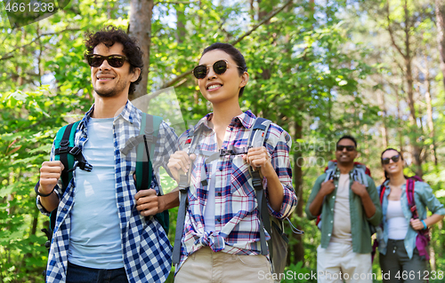 Image of group of friends with backpacks hiking in forest