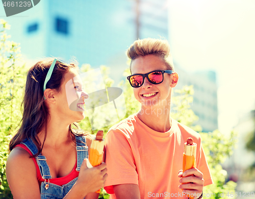 Image of happy teenage couple eating hot dogs in city