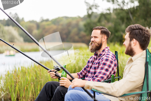 Image of male friends fishing and drinking beer on lake