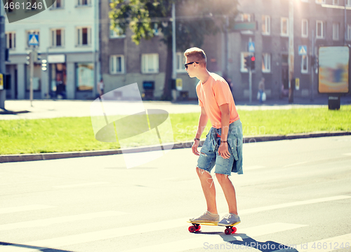 Image of teenage boy on skateboard crossing city crosswalk