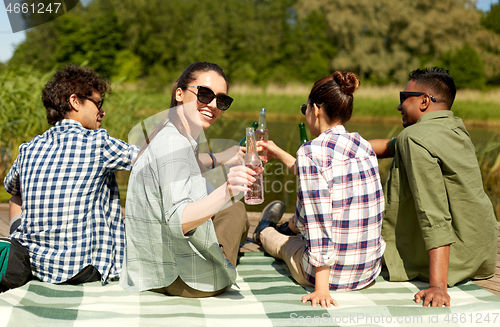 Image of friends drinking beer and cider on lake pier