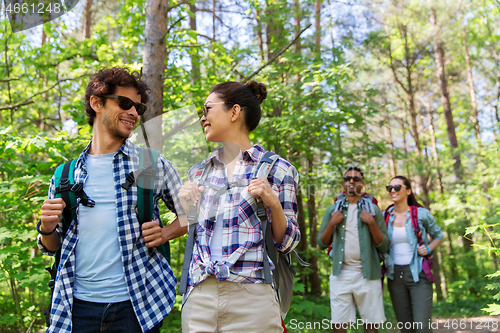 Image of group of friends with backpacks hiking in forest