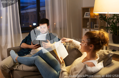 Image of couple with tablet computer and book at home