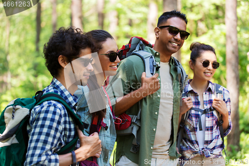 Image of group of friends with backpacks hiking in forest