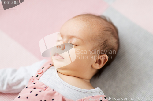 Image of sleeping baby girl in pink suit lying on blanket