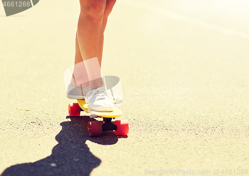 Image of legs of young woman riding skateboard on road