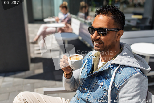 Image of indian man drinking coffee at city street cafe