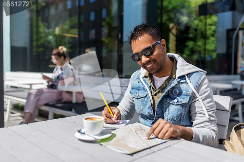 Image of man with map and notebook at street cafe in city