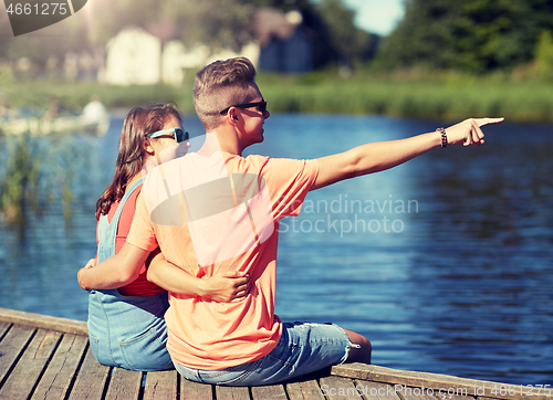 Image of happy couple pointing finger on summer river berth