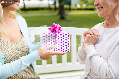 Image of daughter giving present to senior mother at park