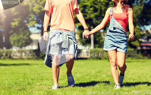 Image of happy teenage couple walking at summer park