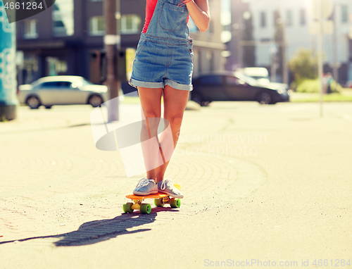 Image of teenage girl riding skateboard on city street