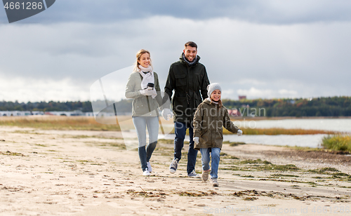 Image of happy family walking along autumn beach