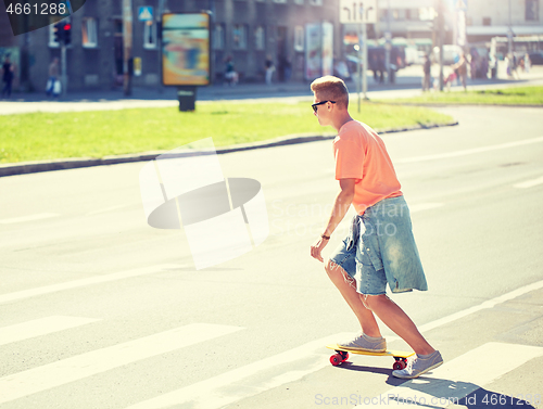 Image of teenage boy on skateboard crossing city crosswalk