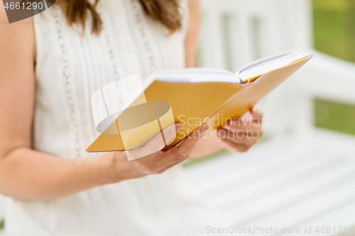 Image of close up of young woman reading book at park