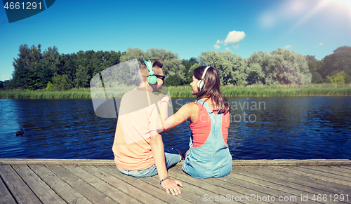 Image of teenage couple with headphones on river berth