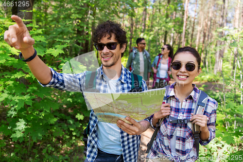 Image of friends with map and backpacks hiking in forest