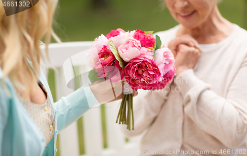 Image of daughter giving flowers to senior mother at park