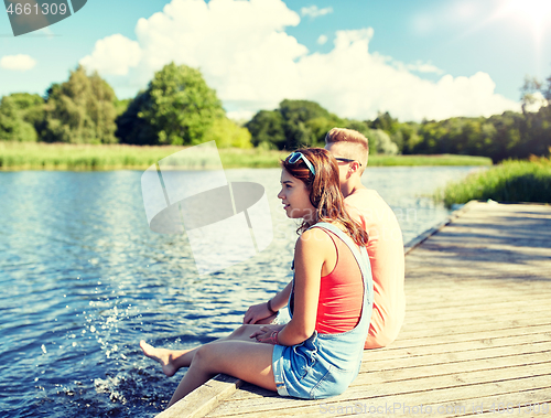 Image of happy teenage couple sitting on river berth