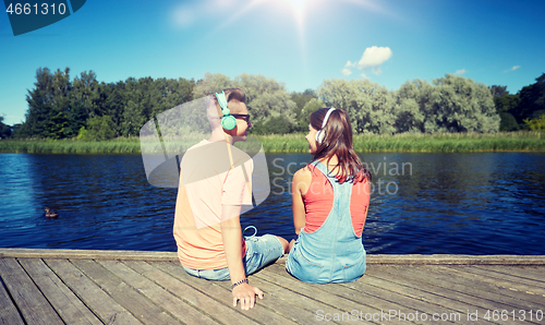 Image of teenage couple with headphones on river berth