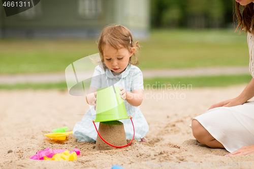 Image of little baby girl plays with toys in sandbox