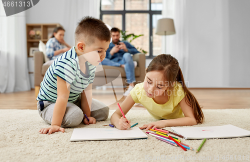 Image of brother and sister drawing with crayons at home