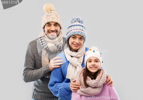 Image of happy family in winter clothes on grey background