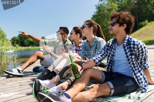 Image of friends drinking beer and cider on lake pier