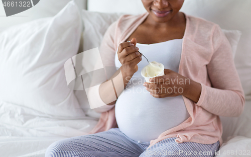Image of pregnant woman eating yogurt for breakfast in bed