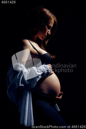 Image of Profile of pregnant woman over black background