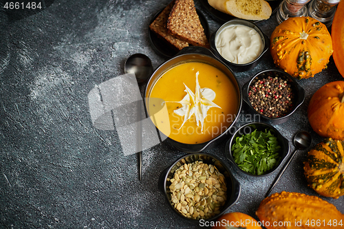 Image of Delicious pumpkin soup with cream, seeds, bread and fresh herbs 